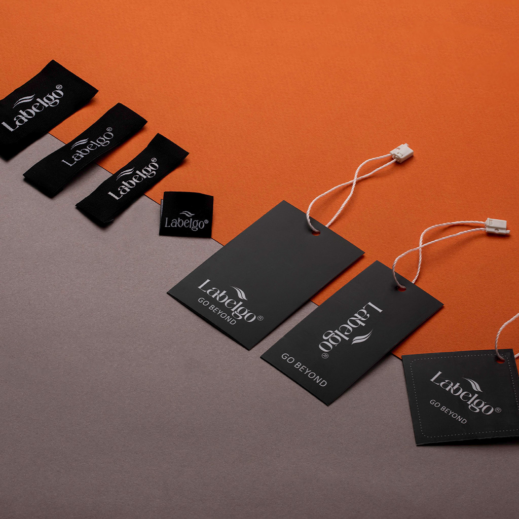 Black textile hang tag labels with strings displayed on surface.