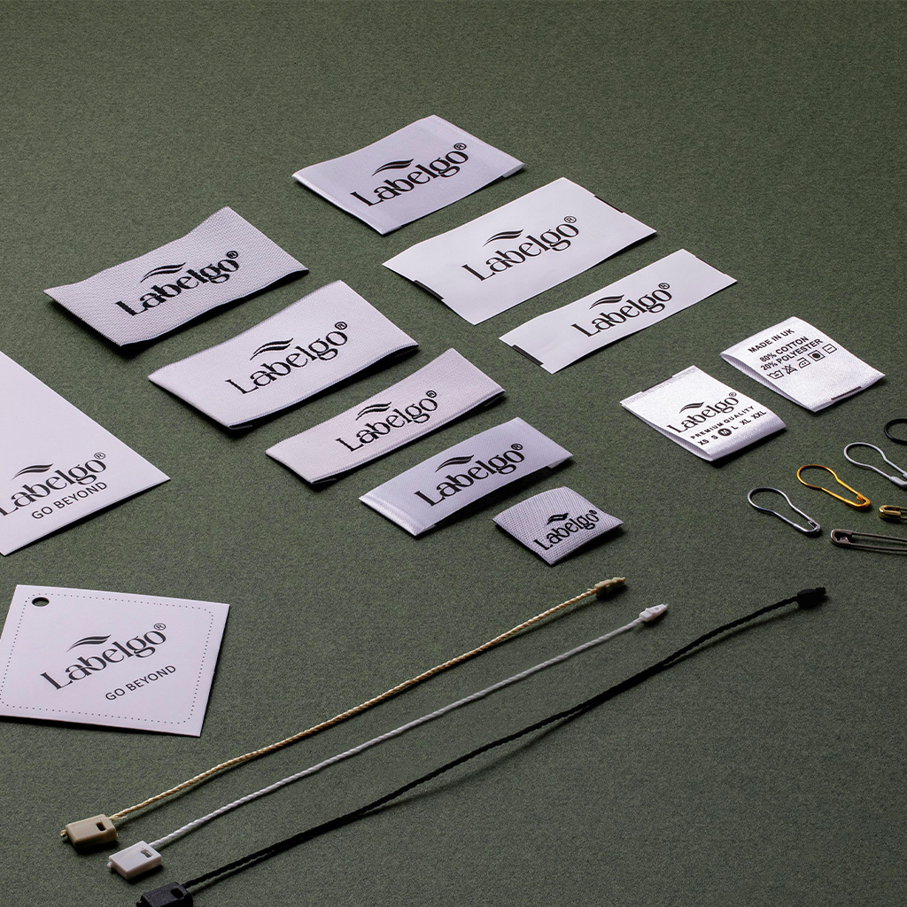 White woven clothing labels displayed on grey fabric.