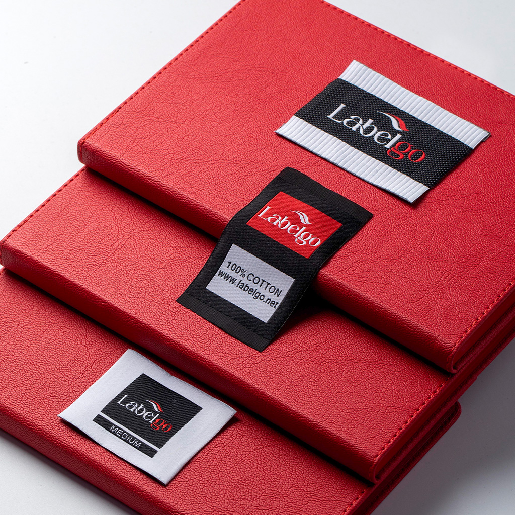 Black and red woven clothing labels arranged on red fabric.