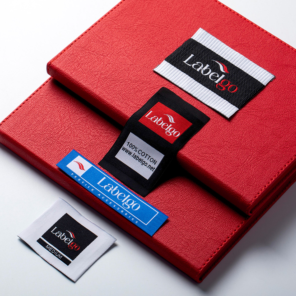 Assorted woven clothing labels arranged on red material.