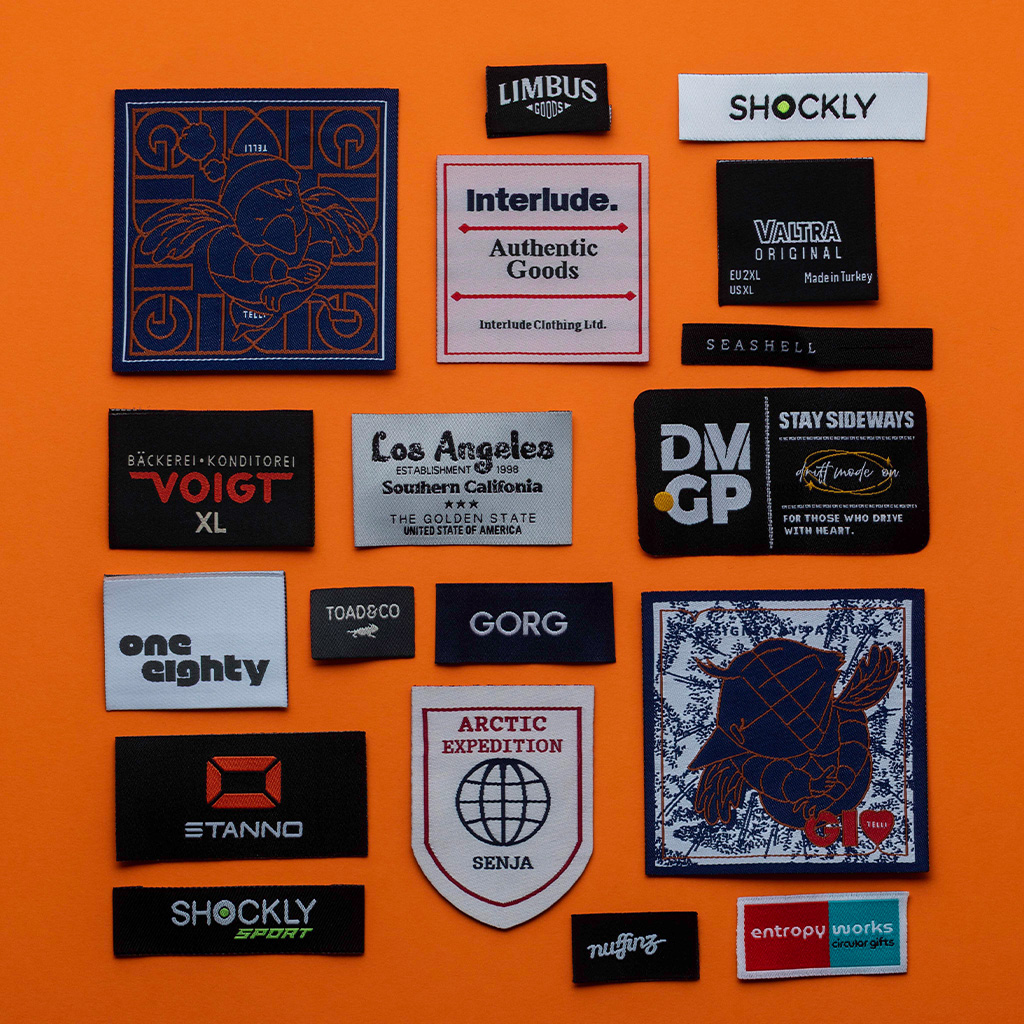 Assorted woven brand labels placed on orange background.
