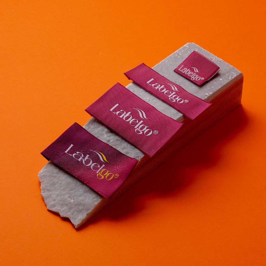 Burgundy woven satin labels placed on orange background.